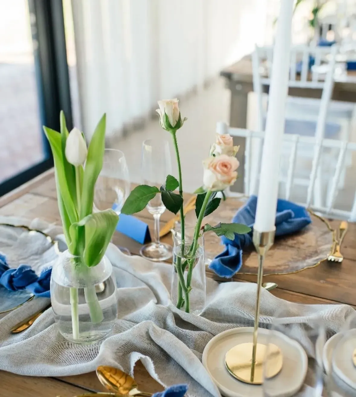 A blue-themed table setting with tulips, roses, and gold candlesticks.