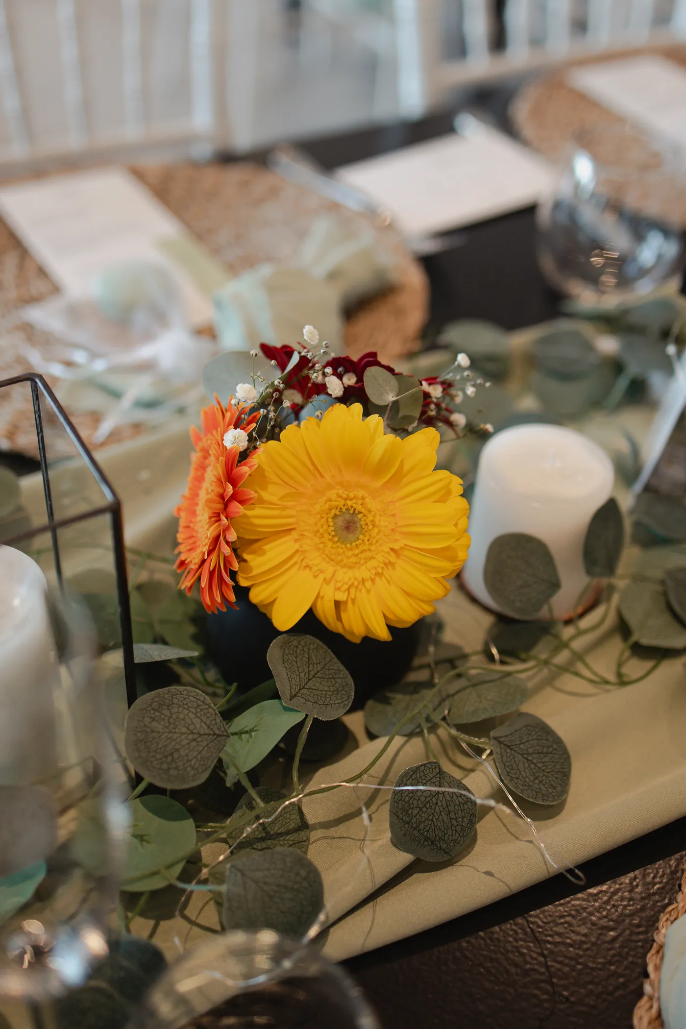 A colorful gerbera daisy centerpiece on a sage green table runner.
