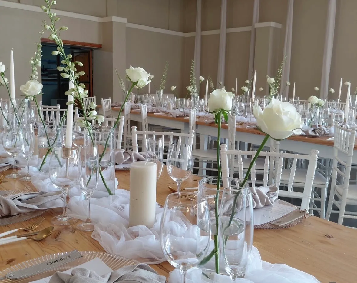 A long table styled with taper candles, delphinium, and handwritten place cards.