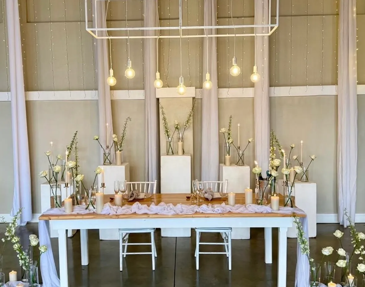 A long reception table set with white chiavari chairs and garden roses.