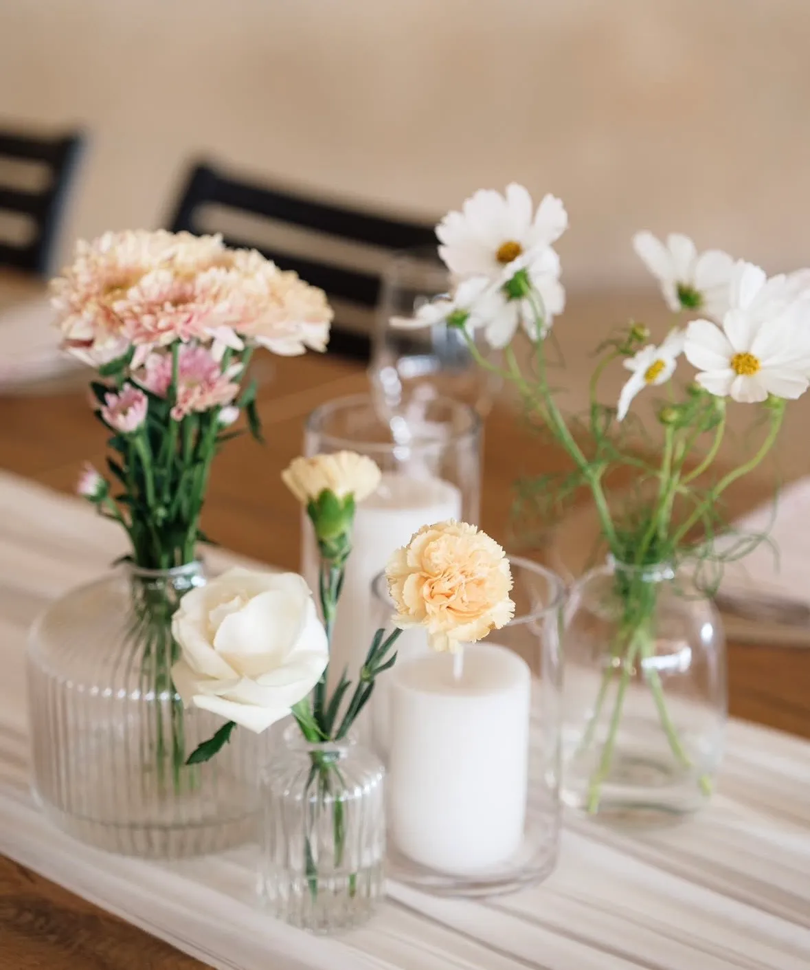 A bud vase centerpiece styled on a wooden table.